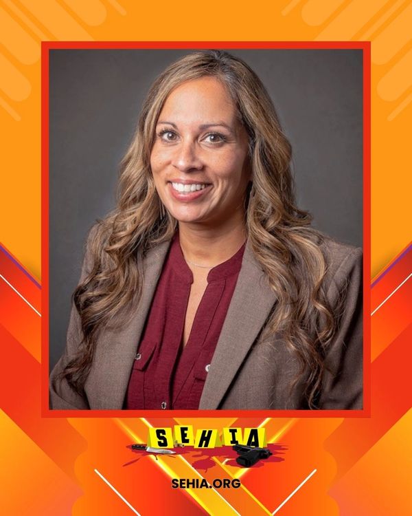 Professional woman in a blazer smiling at the camera with SEHIA branding.