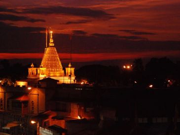 Illuminated temple at sunset with orange sky.