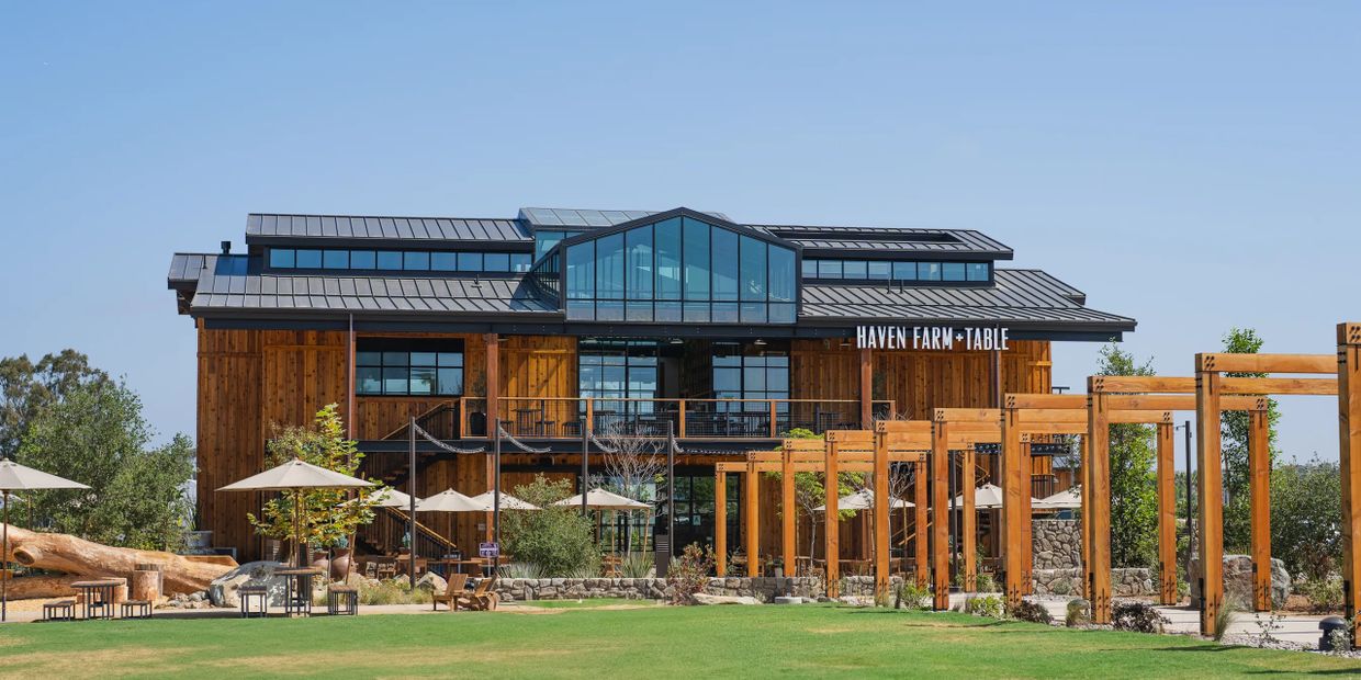 Modern wooden building with outdoor seating and pergola at Haven Farm + Table.