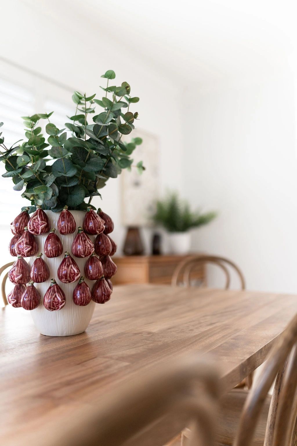 Decorative vase with green foliage on wooden table.