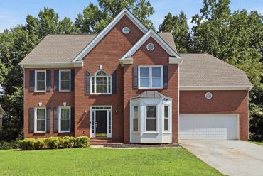 Two-story brick house with a green lawn.