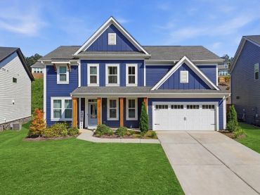 Blue two-story house with white trim and a spacious driveway.