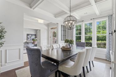 Bright dining room with large windows and elegant chandelier.