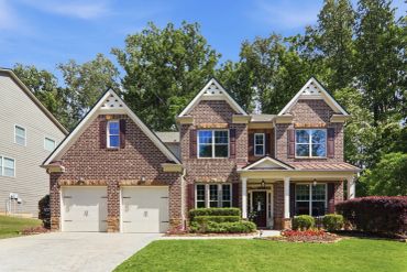 Elegant brick two-story suburban house with a manicured lawn and double garage.