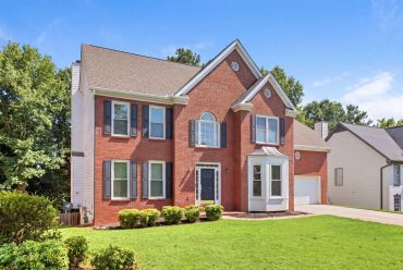 Two-story brick house with a green lawn.