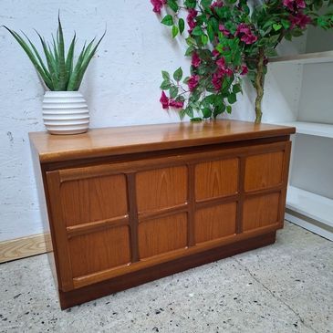Wooden sideboard with plants on top.
