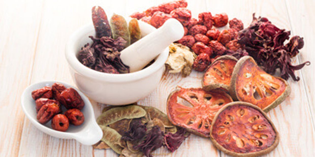 Colorful Chinese Herbs are on a plate with a grinder. 