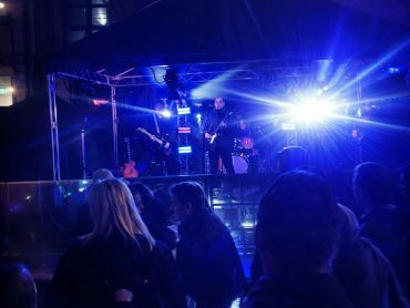 Band performing live on stage with blue lighting and audience watching.