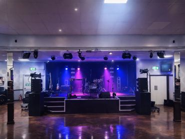 Empty stage with purple lighting and musical instruments set up.