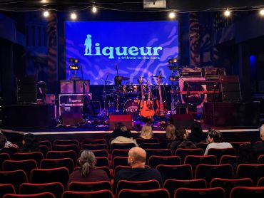 Audience waits in a theater for a live band performance called Liqueur.