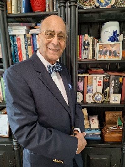 an old man standing near a book self