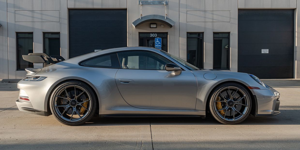 Silver sports car parked in front of a building with large garage doors.