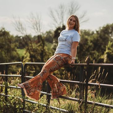 Owner sitting on fence in field