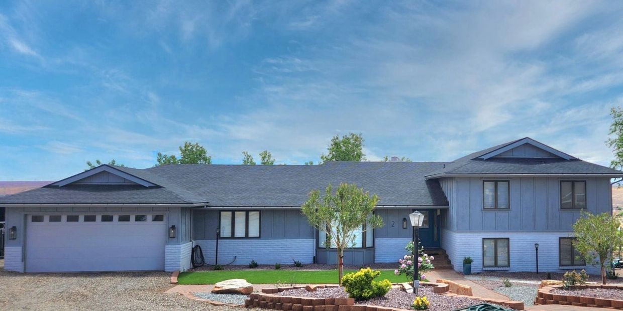 Single-story blue-gray house with a large garage and landscaped front yard.