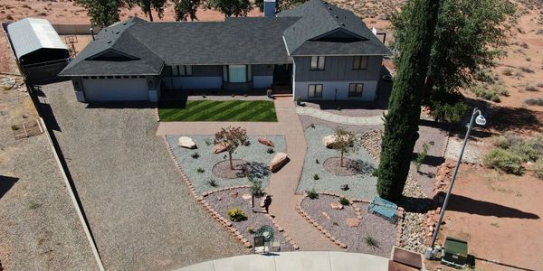 A single-story house with a large gravel driveway and landscaped front yard in a desert area.