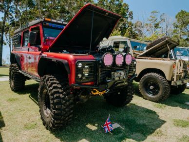 Two off-road SUVs with open hoods at a car show.