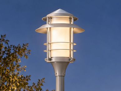 Modern outdoor street lamp glowing against evening sky.