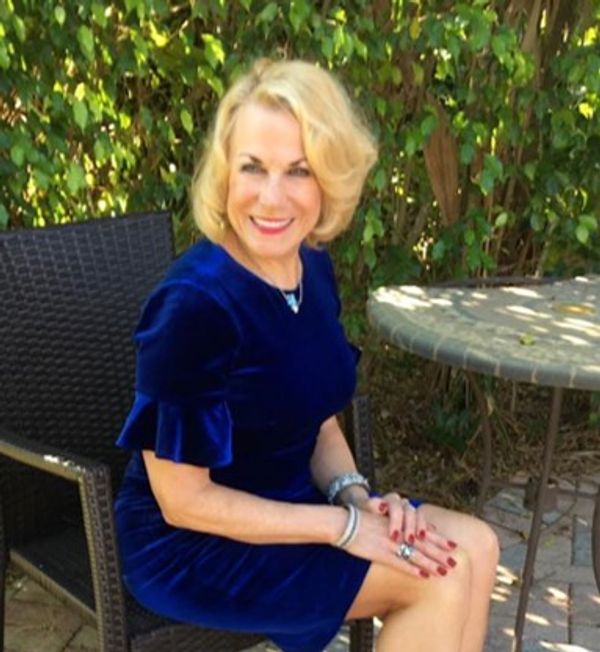Dr. Jacalyn Kerbeck in a blue dress sitting outside. 