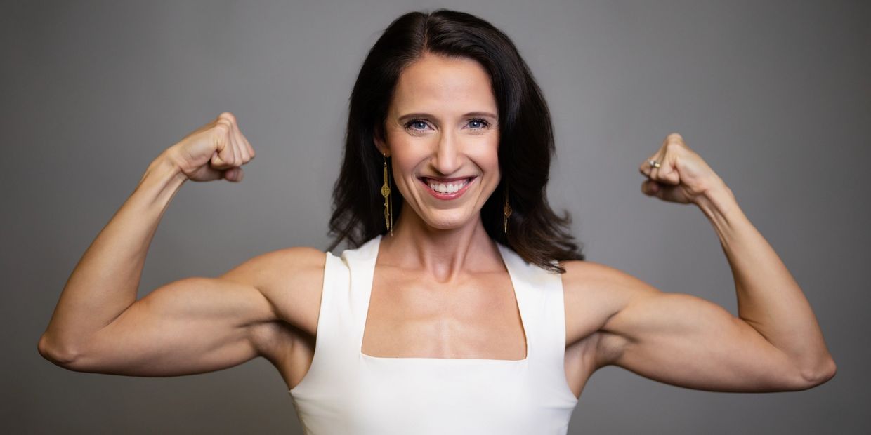 A confident woman flexing her muscles and smiling.