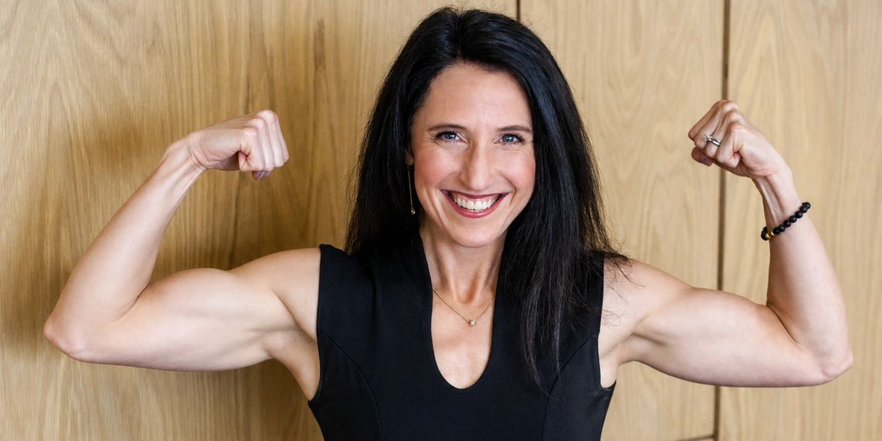 Smiling woman flexes her toned arm muscles confidently.