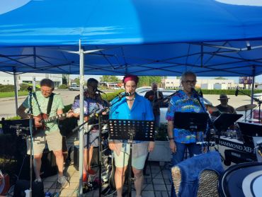 Band spielt unter blauem Zelt draußen.
