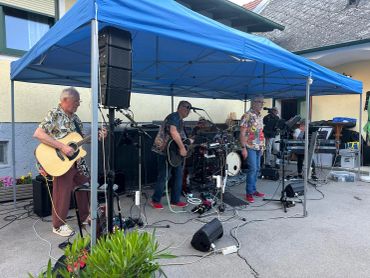 Band spielt live unter einem blauen Pavillon.