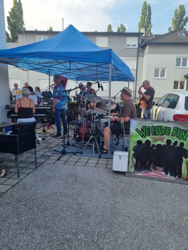 Band spielt live unter blauem Pavillon im Freien.