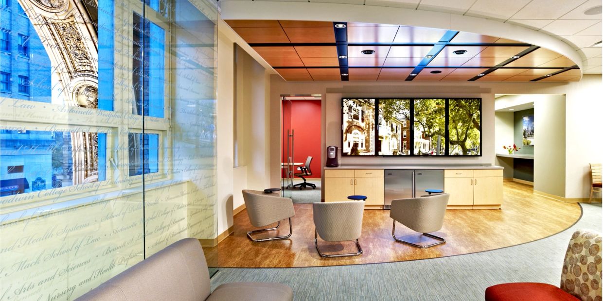Modern office lounge area with chairs and a large screen.