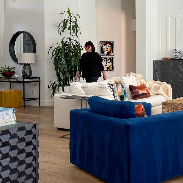 Woman standing in a stylish living room with colorful furniture and modern art.