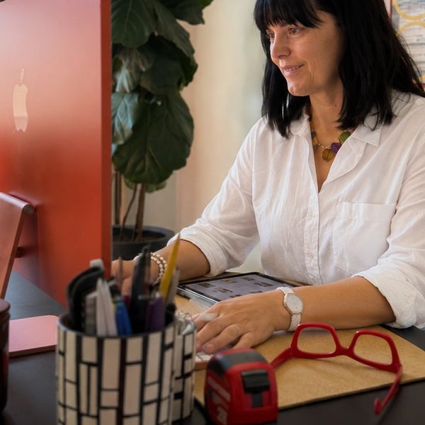 Woman working on a tablet at her desk with office supplies around.