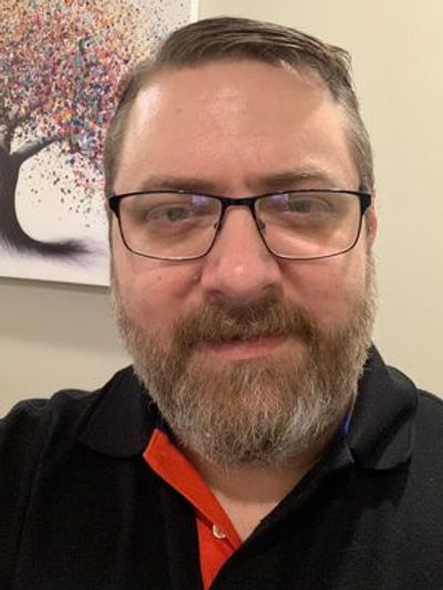 A man with glasses and a beard smiling.