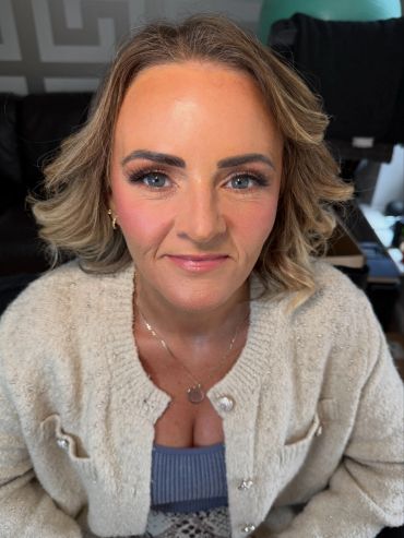 Smiling woman with styled hair and light makeup.