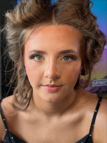 Close-up of a young woman with styled hair and makeup.