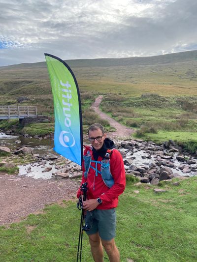 Man holding a flag with natural landscape in the background.
