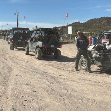Off-road vehicles lined up on a dirt path in a desert area.