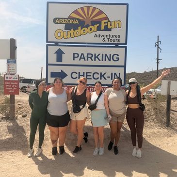 Group of six friends posing happily near an Arizona Outdoor Fun sign.