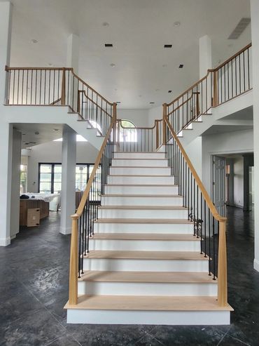 Elegant wooden staircase with black iron balusters in a spacious modern home.