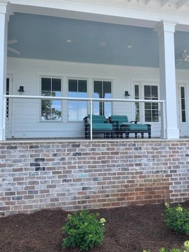 Cozy porch with teal chairs and brick foundation under a covered patio.