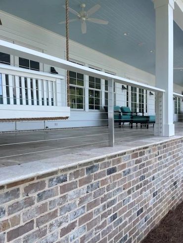 Cozy porch with a hanging swing and seating area on a brick foundation.
