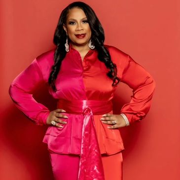Woman in red and pink silky outfit posing confidently.