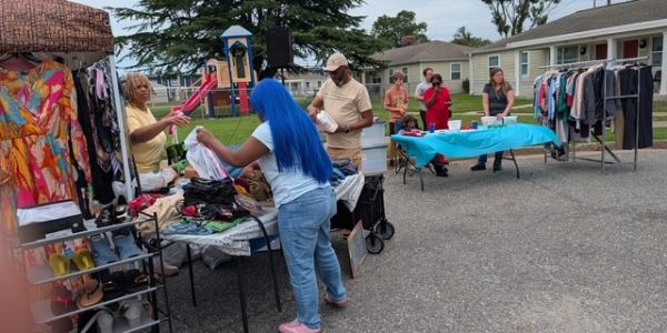 People shopping at an outdoor clothing sale.