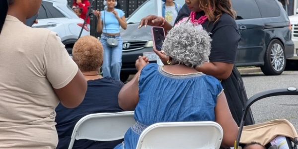 People gathered outdoors, some seated, some standing.