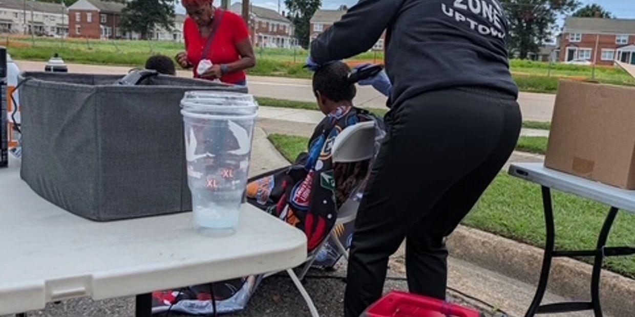 Outdoor haircutting event with people on chairs.