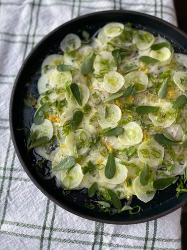 Fresh cucumber salad with herbs on a black plate.