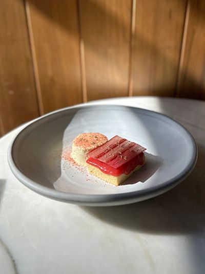 Elegant dessert with red topping and creamy side on a gray plate.