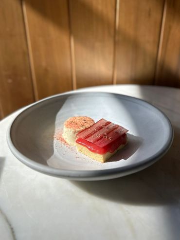 Elegant dessert with red topping and creamy side on a gray plate.