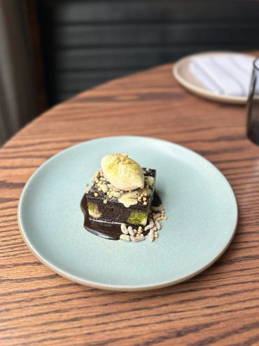 Elegant chocolate dessert with ice cream and crunchy toppings on a blue plate.
