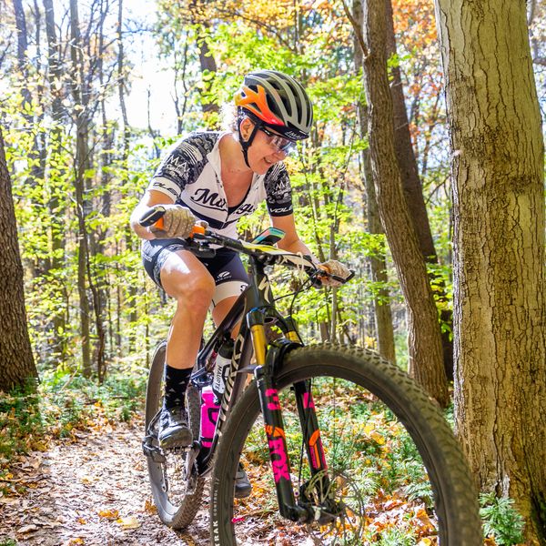 Woman mountain biking on a forest trail in fall.