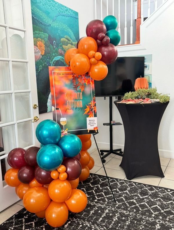 Colorful autumn-themed balloon decoration and welcome sign for a paint and sip event.