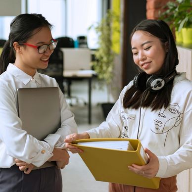 Two women discussing documents in an office setting.